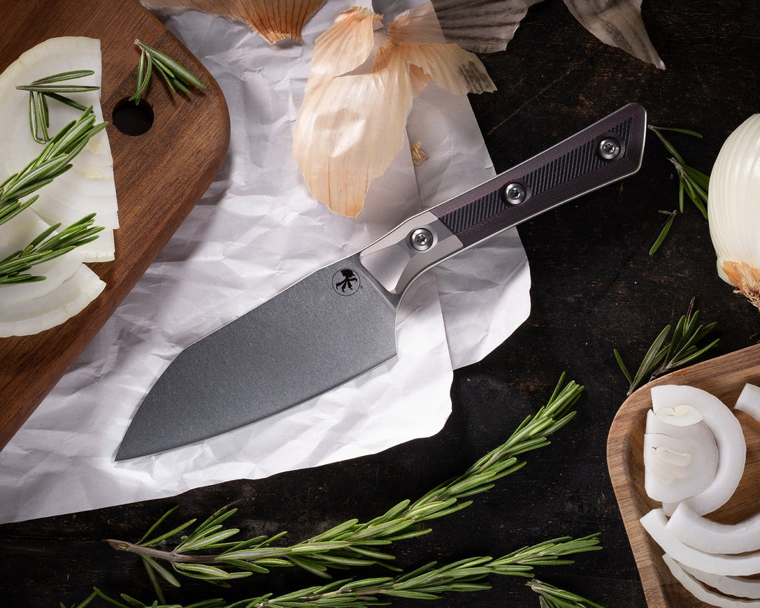 Santoku knife with black handle on parchment paper, onions, rosemary, and cutting board