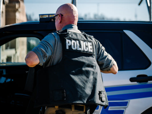 Police officer in tactical vest beside patrol car outdoors