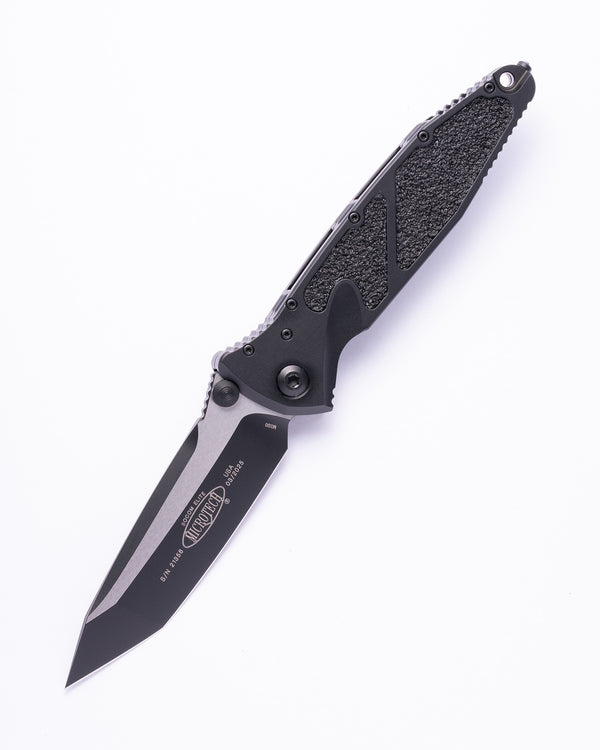 Black tactical folding knife with textured handle and tanto blade on white background
