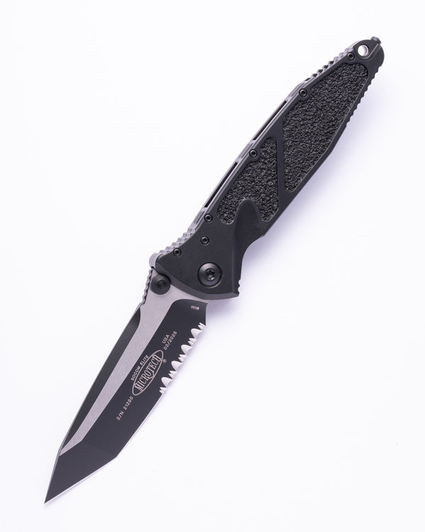 Microtech folding tactical knife with tanto serrated blade on white background