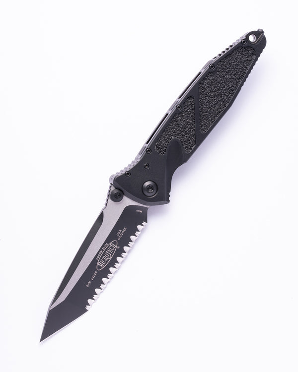 Microtech black folding knife with partially serrated tanto blade on white background