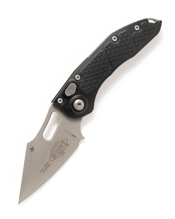 A black and silver Microtech automatic folding knife with a single edged style blade, tri grip textured alloy handle, and double blasted hardware.