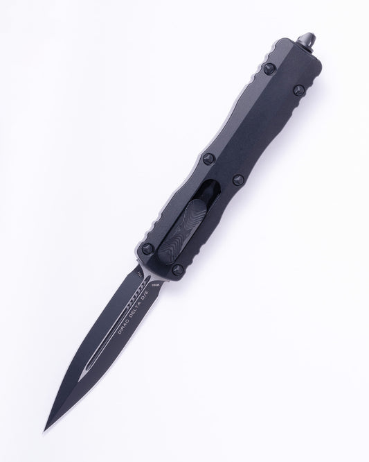 Black tactical OTF knife with serrated blade and textured handle on white background