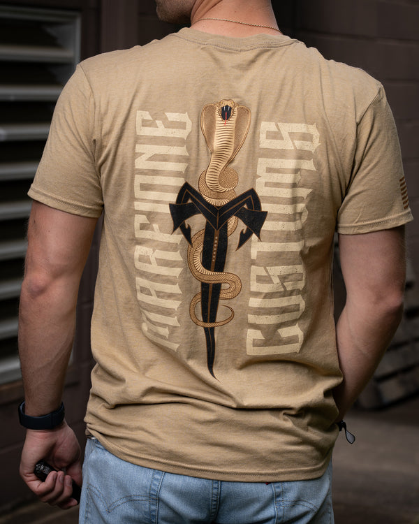 Person wearing a sand tan t-shirt with a snake  and knife design on the back